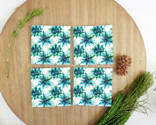 a wooden table topped with four coasters covered in blue and white flowers